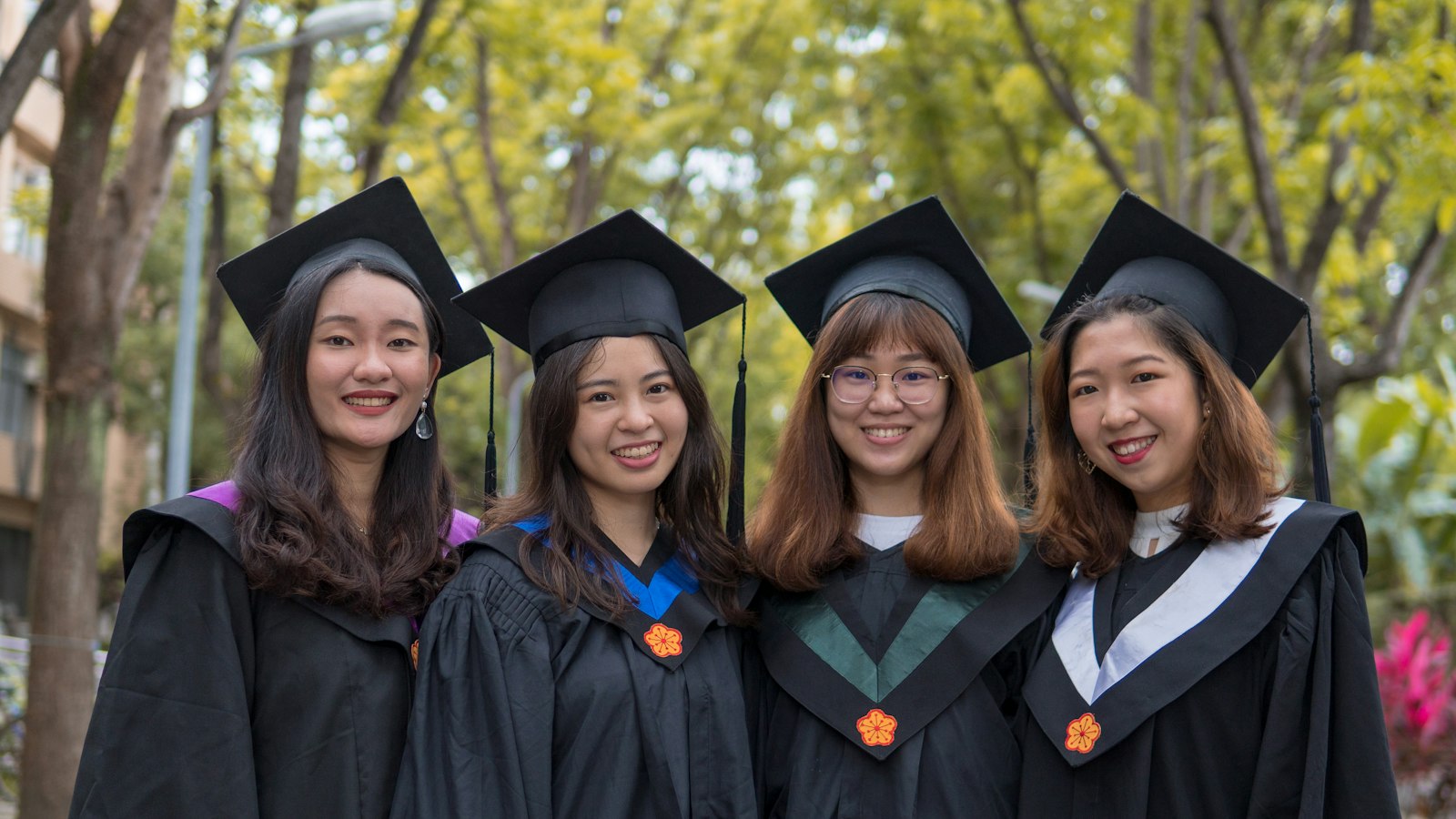 Empat lulusan baru bertoga tersenyum setelah wisuda